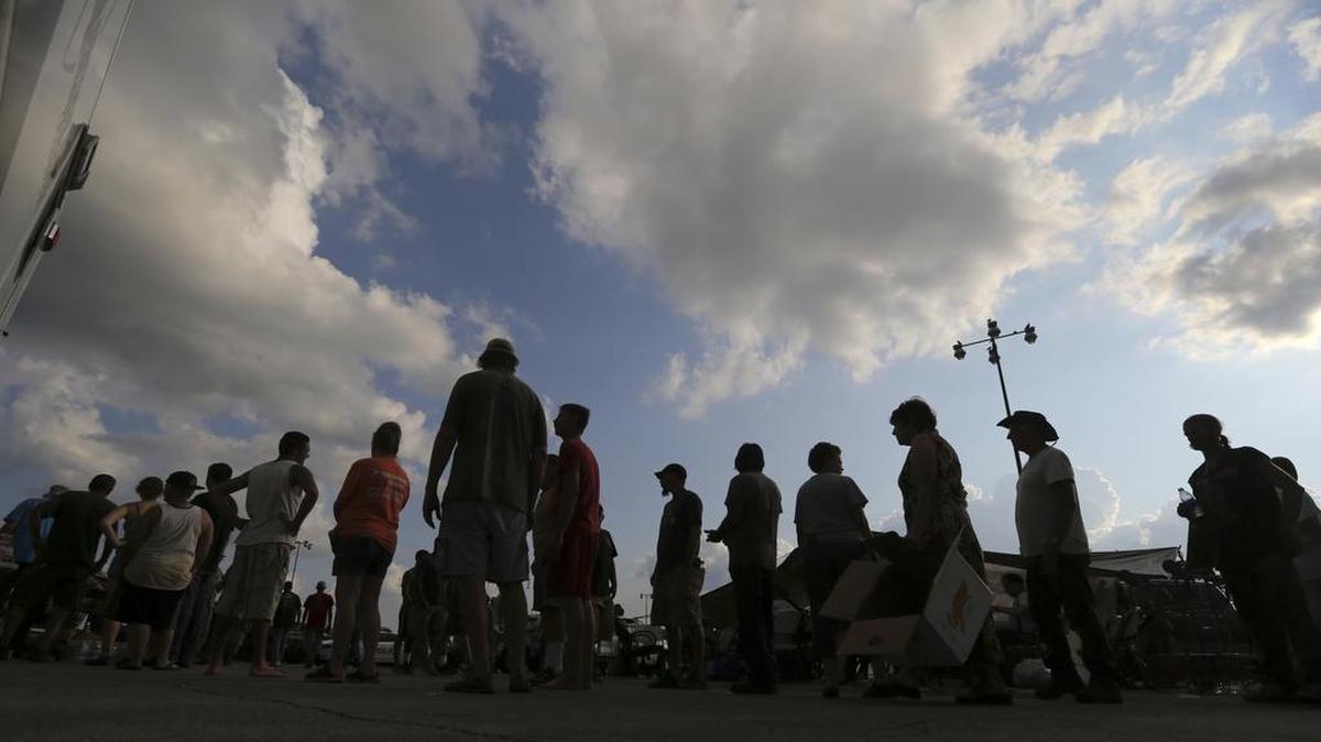 Evacuees who were rescued by boat and high water vehicles stand in line for food being served by volunteers, in the aftermath of Tropical Storm Harvey, in a staging area as they wait for buses to go to evacuation shelters, in Vidor, Texas, on Friday.