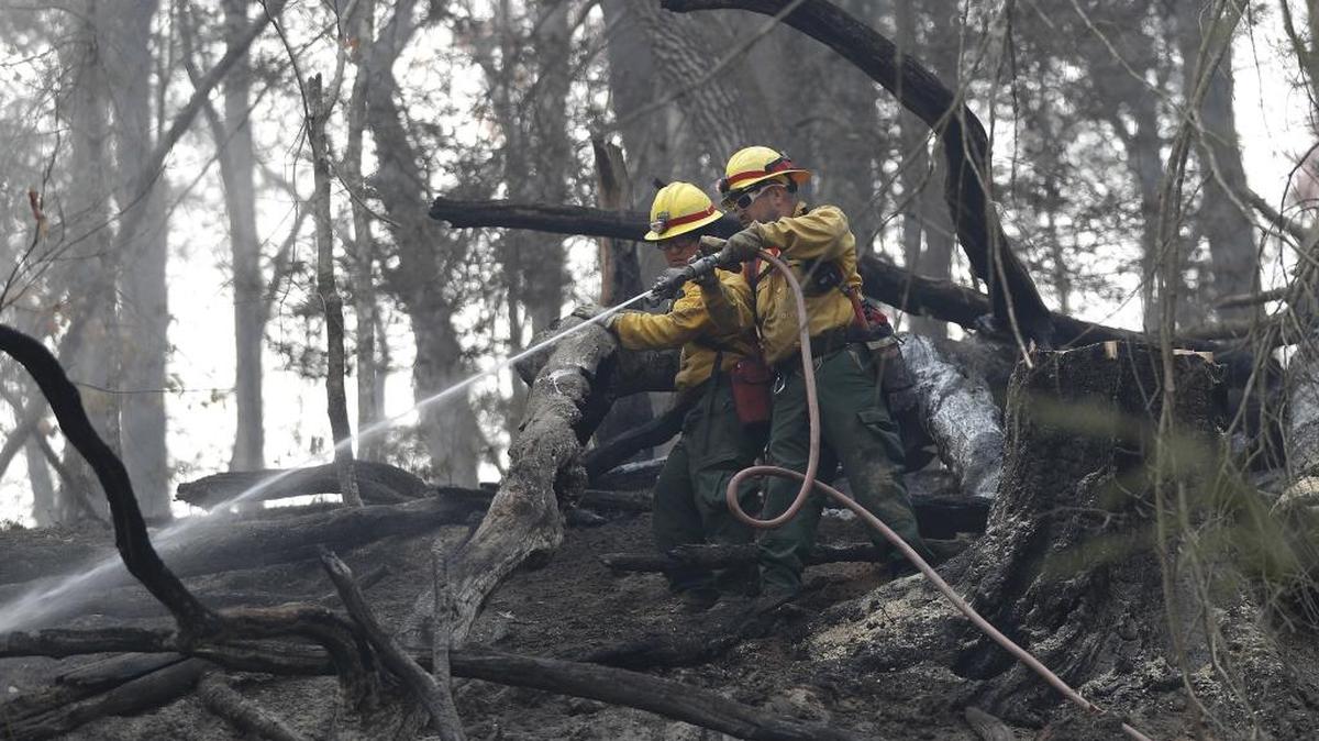 Firefighters Valarie Lopez, left, and Mark Tabaez work to cool hot spots after a wildfire burned a hillside in Clayton, Ga on Tuesday. More than 5,000 firefighters and support personnel, including many veterans of wildfires in the arid West, and 24 helicopters are reinforcing local crews in the fire zone, which has spread from northern Georgia and eastern Tennessee into eastern Kentucky, the western Carolinas and parts of surrounding states