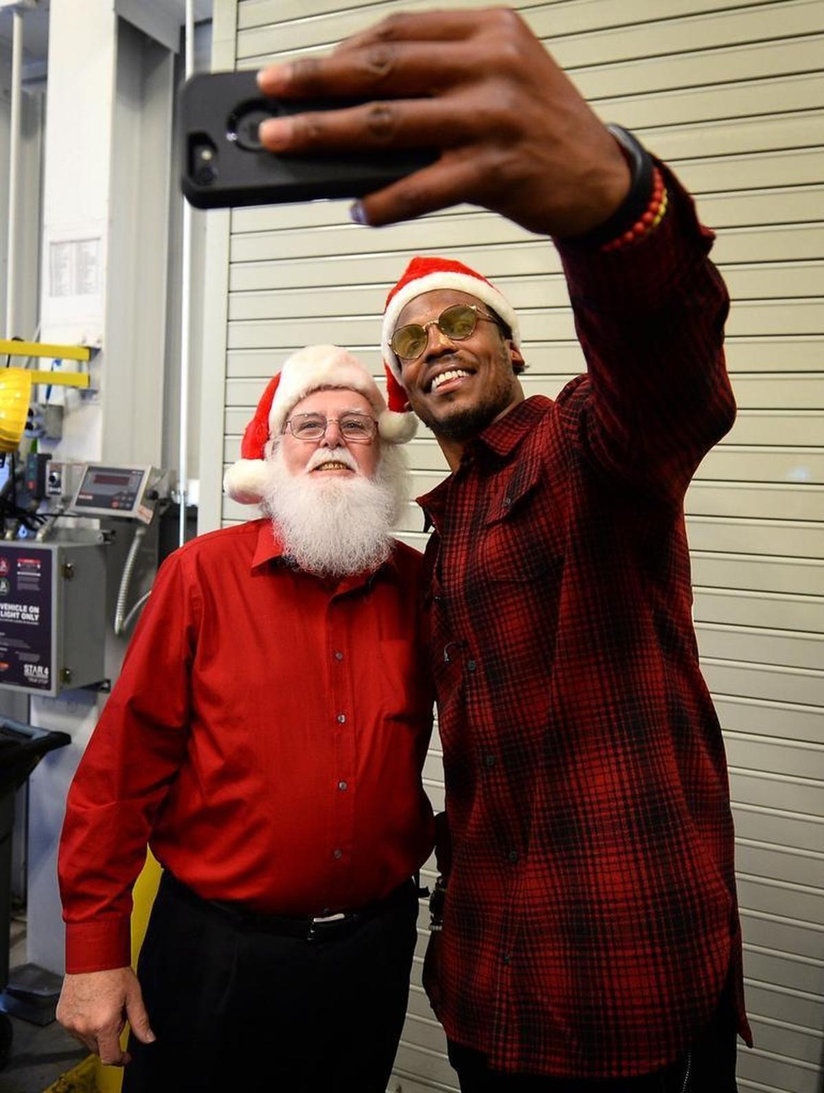 Carolina Panthers quarterback Cam Newton, right, takes a photograph with a participant at Second Harvest Food Bank’s Senior Surprise! event on Tuesday.