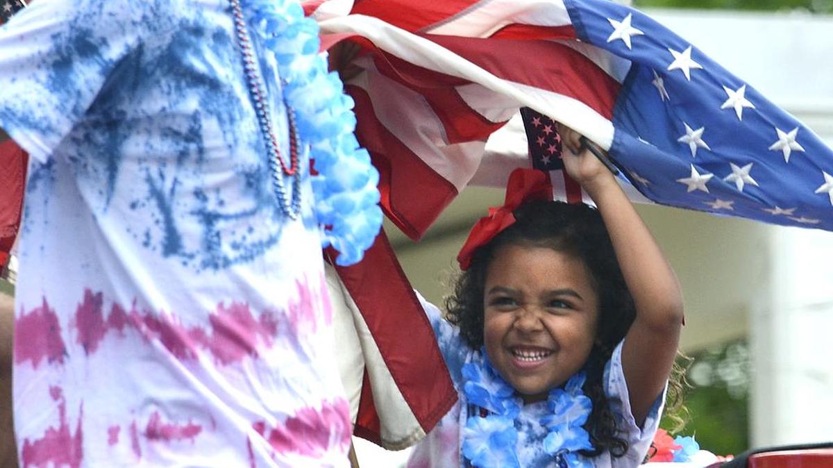 Makala Michelle fends off a large U.S. flag dipped onto her head by Luke Dodge before the start of the Coulwood Community 4th of July parade on July 4, 2015.