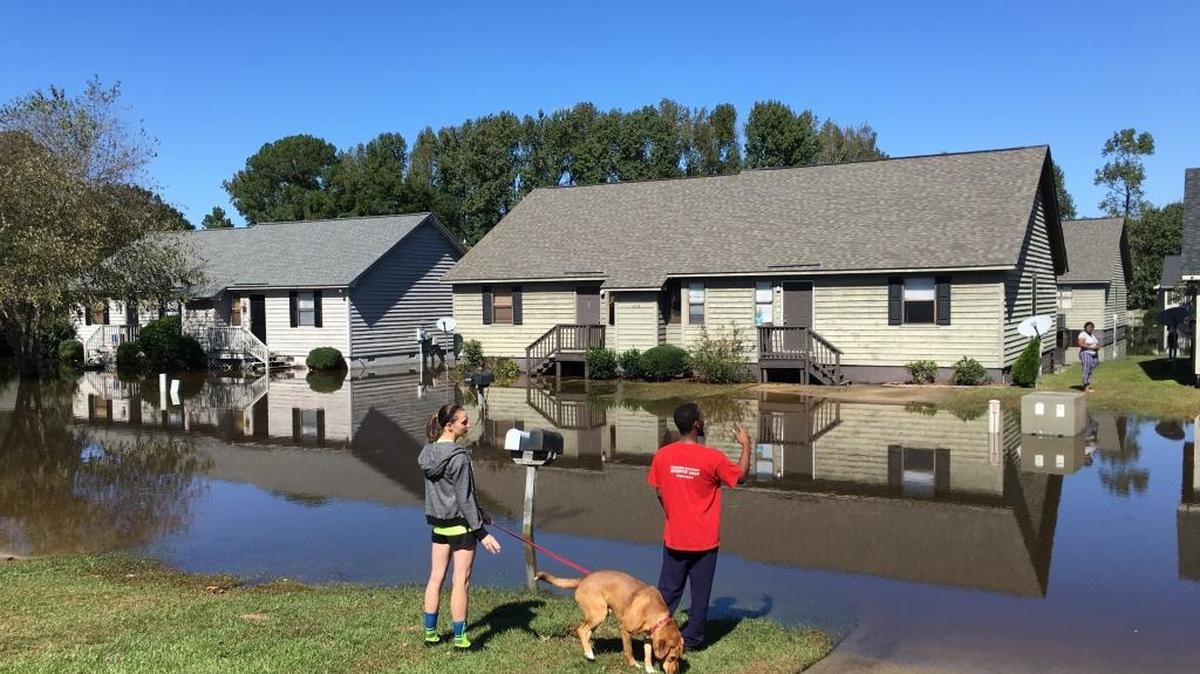 Residents talk across the water as the floodwaters slowly rise at the Wyndham Circle duplex complex in Greenville, NC on Oct. 12, 2016. The complex houses many ECU students.