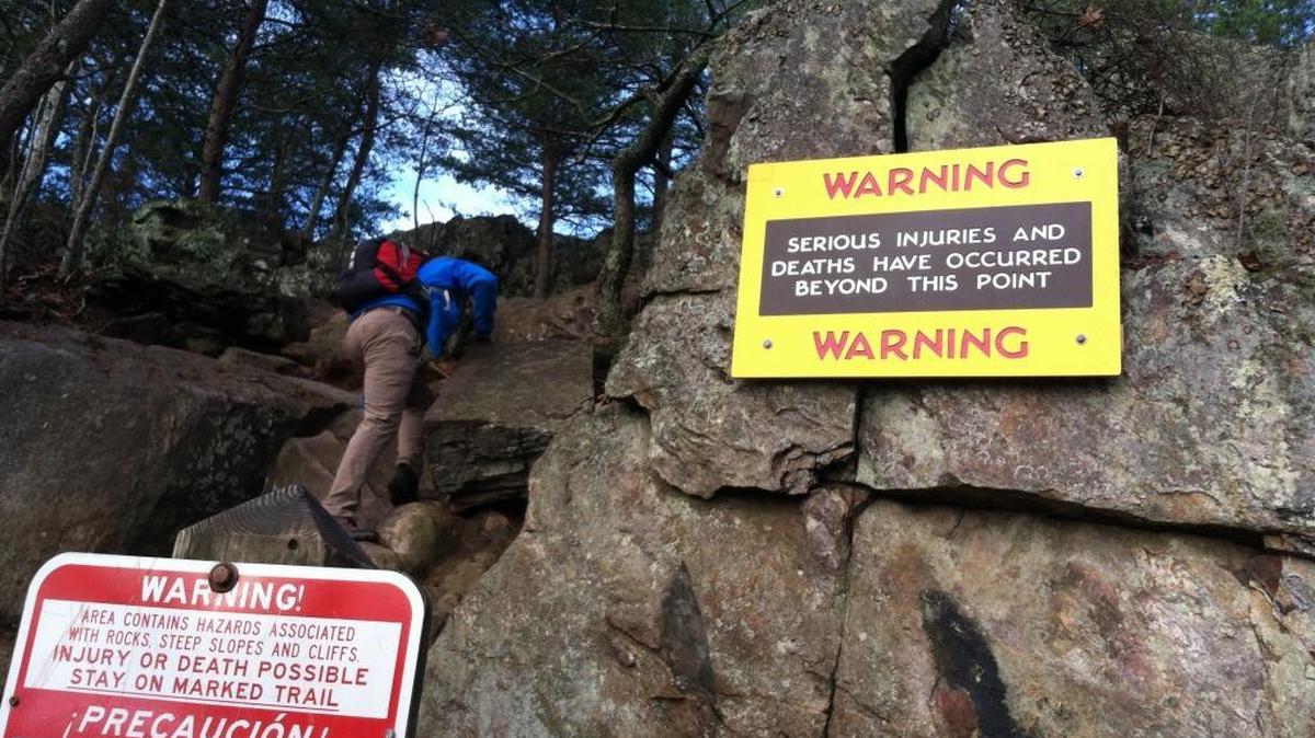 A hiker climbs past a new warning sign at the Pinnacle at Crowders Mountain State Park.