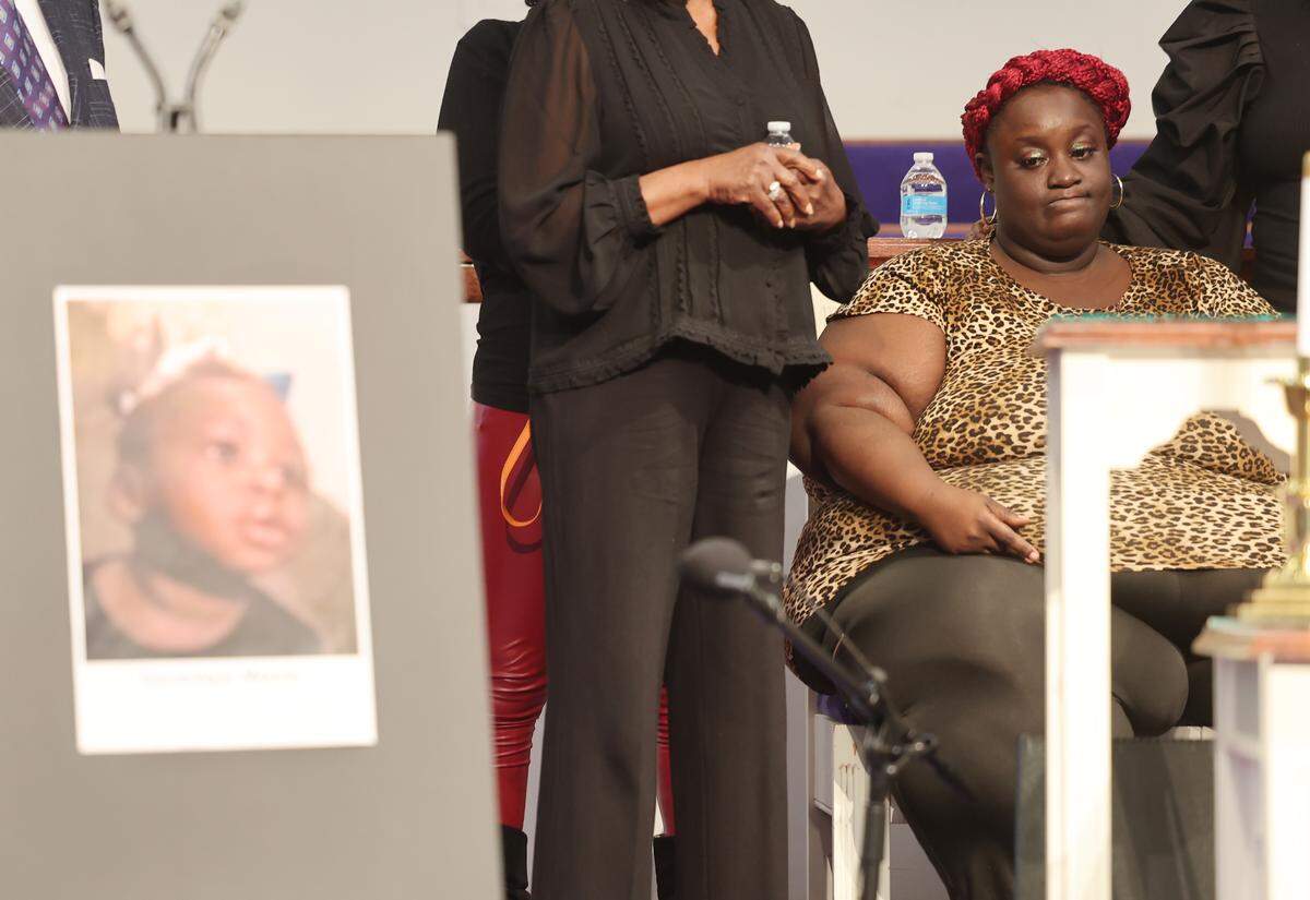 Ikea McKnight, mother of Dominique Moody, shown in a picture on the left, sits onstage at a press conference Monday, March 9, 2026 at Ebenezer Baptist Church in Charlotte. Moody died from prolonged injuries while in the custody of her aunt. Lawyers are looking into the details of Moody's death.
