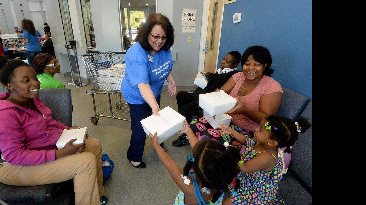 
Crisis Assistance Ministry employee Barbara Guilmette gives out free meals Thursday to Christina Smith, left, Nevaeh Hairston, 4, second from left, Treasure Hairston, 2, third from left, and the two girls' mother Yolanda Maness, right, in the Ministry's lobby Thursday. Crisis Assistance Ministry celebrated its 40th anniversary on Thursday by serving food to people in need waiting in its lobby for help with utility bills and rent. 
