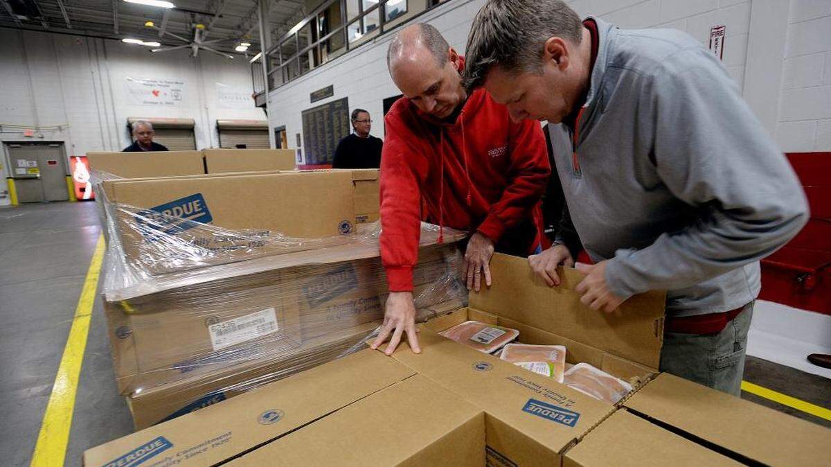
David Brown,left, Second Harvest Food Servicing Manager and Mike Oberle, Second Harvest Child Hunger program coordinator open some of the boxes to see the Perdue package chicken. The two will deliver the package chickens to the families at Winecoff Elementary school. 
