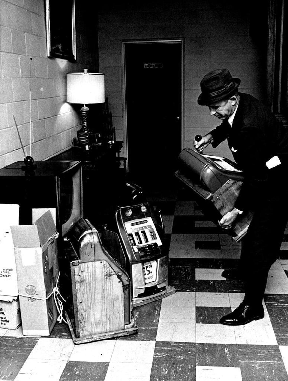 An SBI agent moves a slot machine turned up in the raid at the Gastonia Moose Lodge. June, 1964