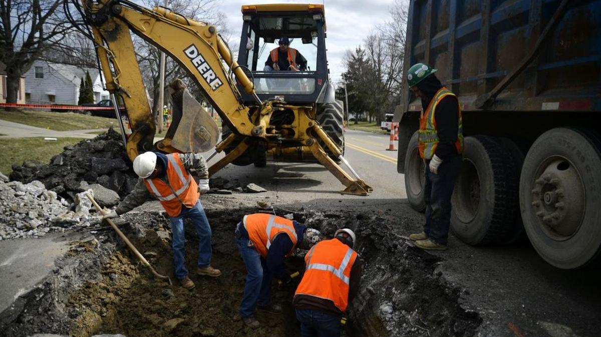 Contractors dig a hole this week to replace a lead water service line in Flint, Mich.