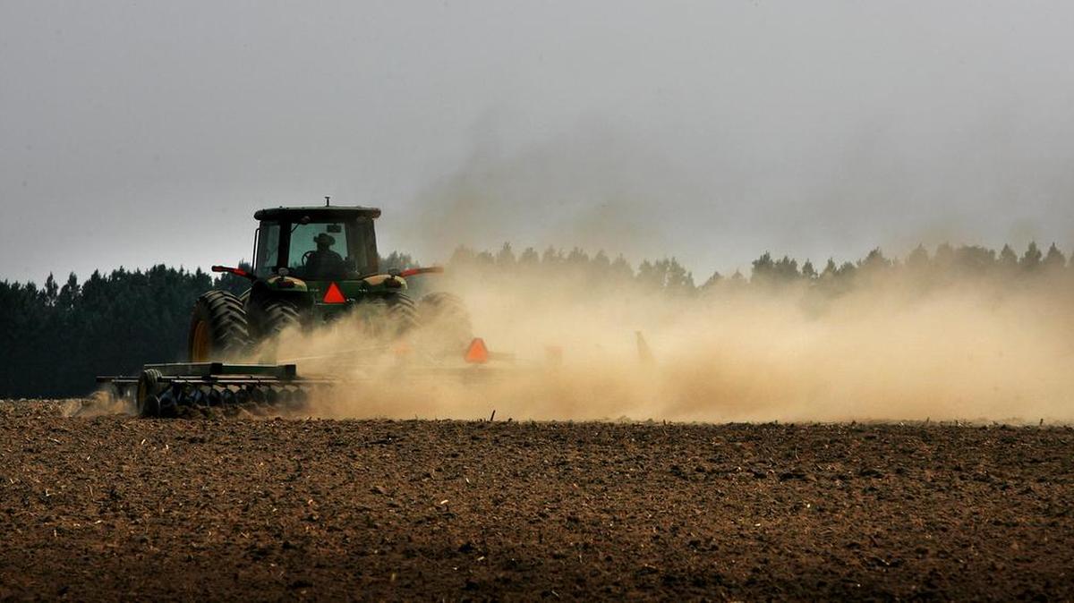 A Walter P. Rawl & Sons worker kicks up a cloud of dust as he plows a field in Pelion in 2011.