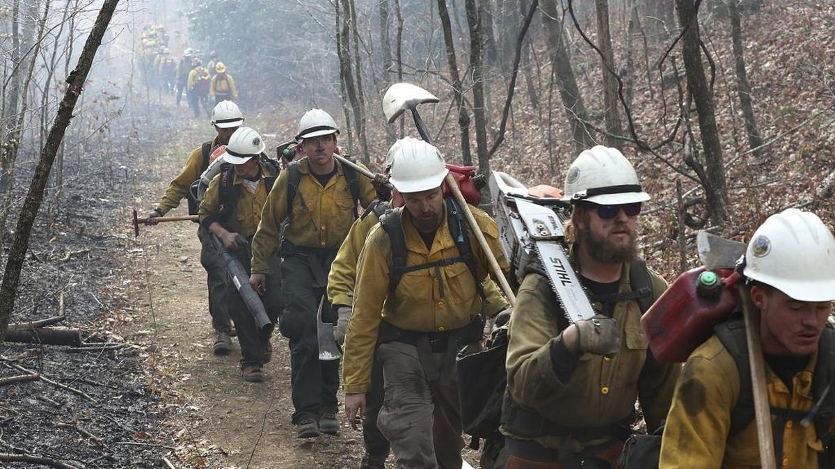 A California fire crew, right, makes their way in after working all night on the northern head of a wildfire along the Appalachian Trail at Deep Gap, north of Tate City and the North Carolina border, while a Oregon fire crew, far left, bumps them heading out for their shift Tuesday.
