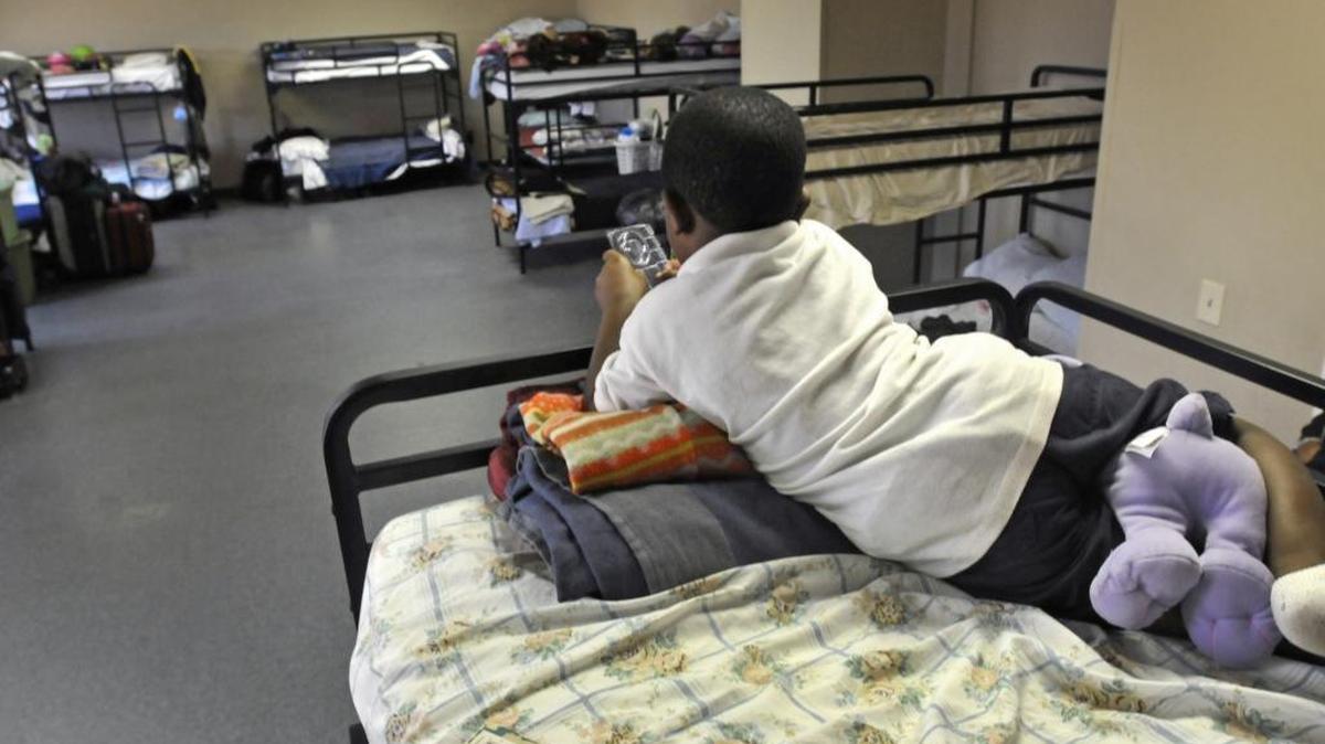 A young boy plays a game on his bunk in a family dorm at the Center of Hope. The Salvation Army shelter is seeking donated play pens for babies so tenants don’t have to sleep doubled up at night.