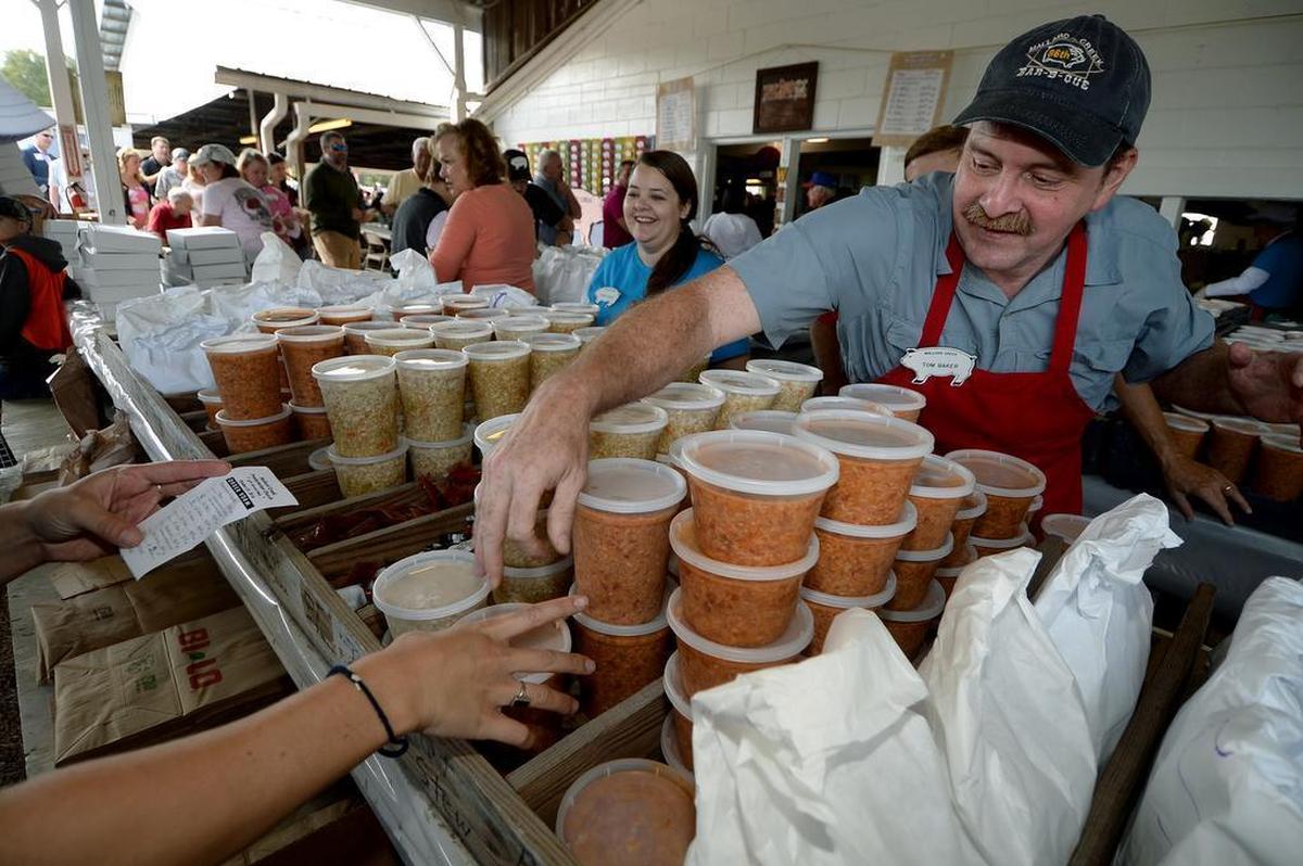 In this 2016 Charlotte Observer photo, Tom Baker puts out containers of stew for takeout drivers at the Mallard Creek BBQ. The 2021 version has been canceled due to concerns over the pandemic.
