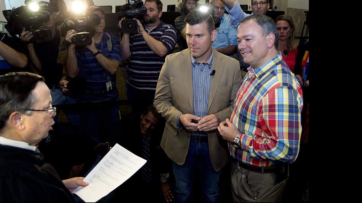 
Chad Briggs (left) and his husband Chris Creech exchange wedding vows as Chief Magistrate Dexter Williams, left, presides at the Wake County Courthouse in Raleigh on October 10, 2014.
