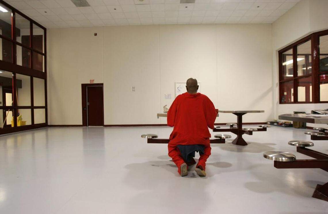 An unidentified death row inmate writes a letter. He’s seated in a common area at Central Prison in Raleigh. Inmates on North Carolina’s death row wear red to signify their status.