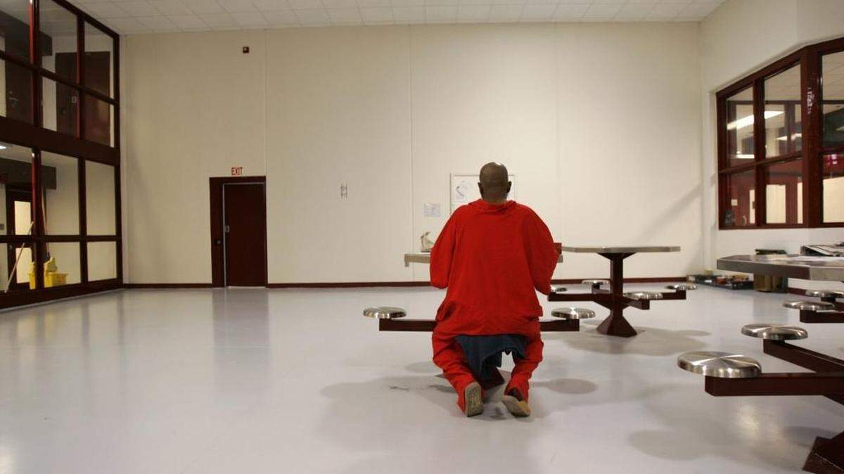 An unidentified death row inmate writes a letter. He’s seated in a common area at Central Prison in Raleigh. Inmates on North Carolina’s death row wear red to signify their status.