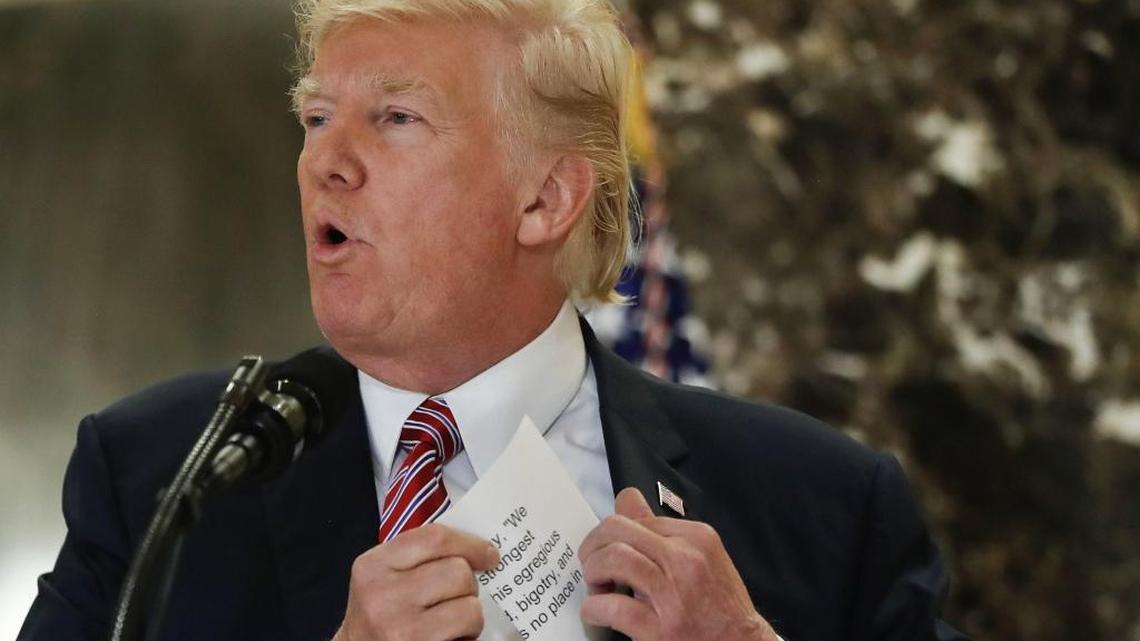 President Trump reaches into his suit jacket on Aug. 15 to read a quote he had made three days earlier about the violence between white nationalists and protesters in Charlottesville, Va. A Charlotte-area evangelical leader says he will continue to serve on a presidential advisory council despite discomfort with Trump’s initial comments on the clash.