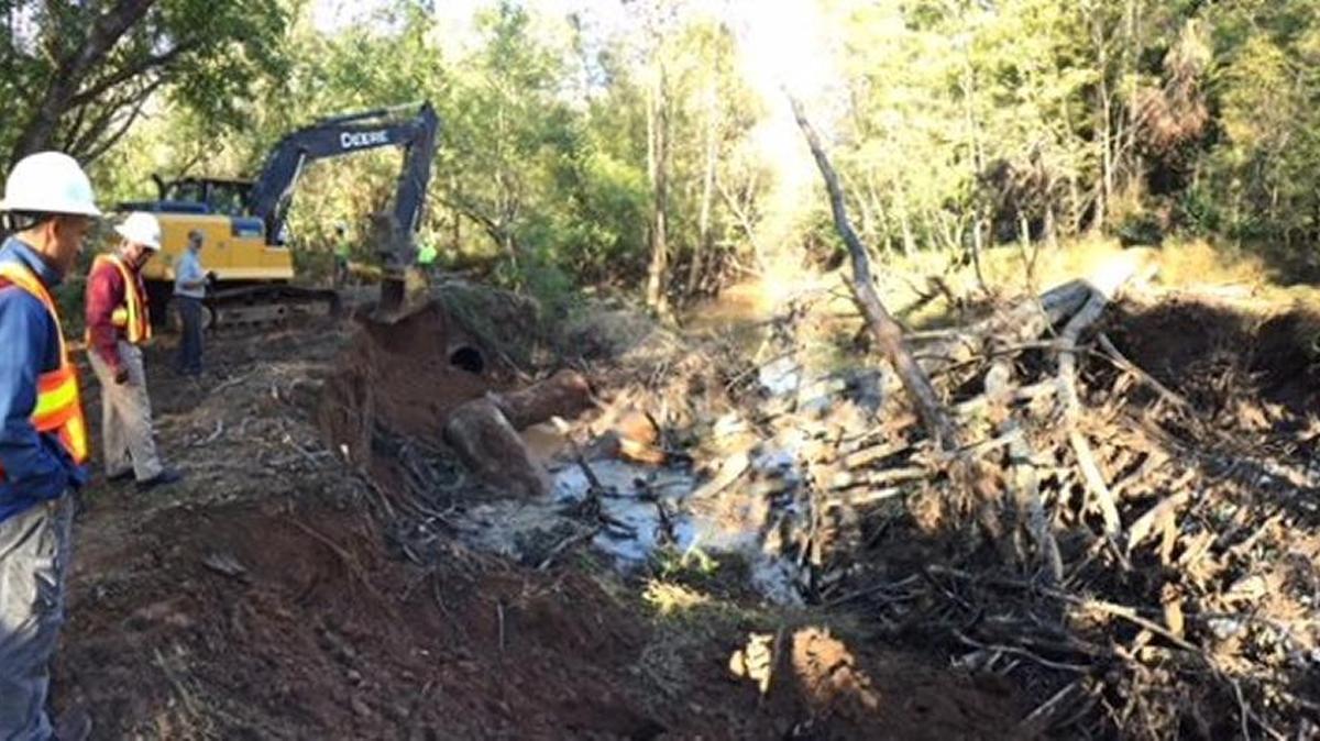 Crews work to repair a broken 36-inch sewer line, on the left side of the creek bank, that spilled 4.7 million gallons of sewage into Mallard Creek.