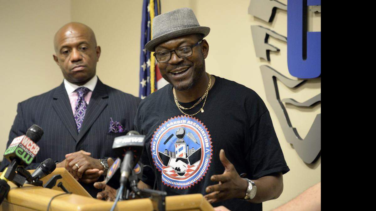
Charlotte-Mecklenburg Police Det. Garry McFadden, left, listens as Gene Winchester, President of the NC Local Barbers Association speaks to the media about the upcoming peace rally called Arms Around Charlotte during a press conference at CMPD Headquarters on Thursday, July 9, 2015. 
