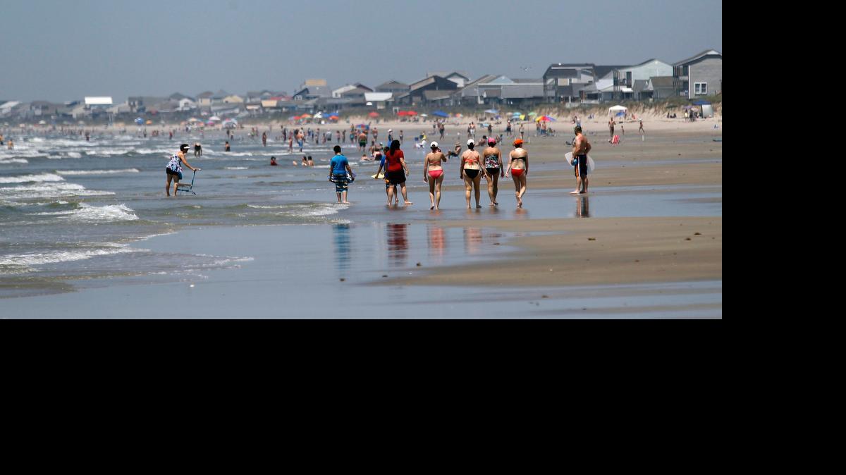 
Beachgoers walk on Oak Island beach looking south from the Ocean Crest Pier on Monday. On Sunday, two people were attacked by sharks while swimming in this southeastern North Carolina town. . On Monday, a few people went into the water, but not very far out. Most were either on the sand or just in the surf where the water was only a foot or two deep.
