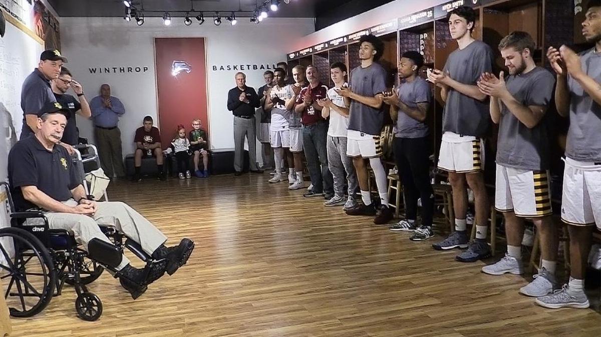 The Winthrop University mens’ basketball team claps for York County officers before a game Sunday. The officers, Randy Clinton, bottom left, and Buddy Brown, center left, of the York County Sheriff's Office and Kyle Cummings, third from left, of the York Police Department, were shot during an ambush in January. Detective Mike Doty was killed during the shooting. Not shown in the photo is Mike Doty’s twin brother, Chris Doty, who also attended the game.