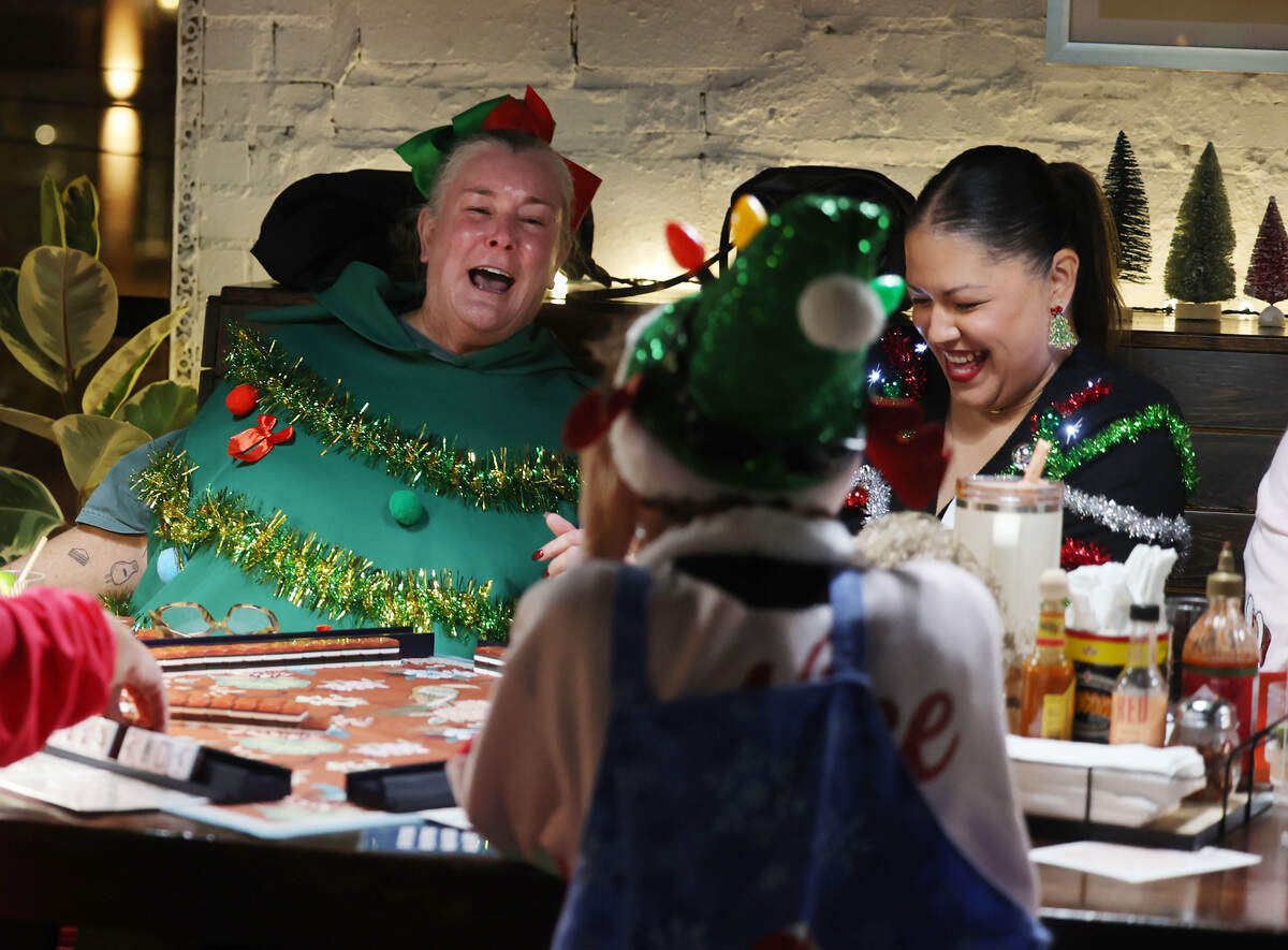 Becky Hoech, left, and Jules Mecias laugh over a game of mahjong during Eastside Mahjong’s ugly sweater event at Salud Cerveceria in Charlotte.