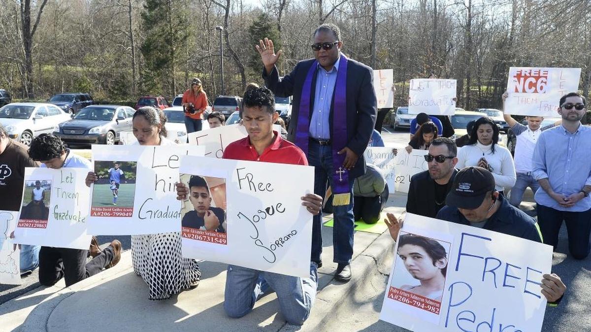 Rev. Rodney Sadler in center, leads a prayer for family members of the NC6 during a protest at at the Department of Homeland Security in Feb. 29. The six teens were part of the first round of local immigration arrests by federal agents..