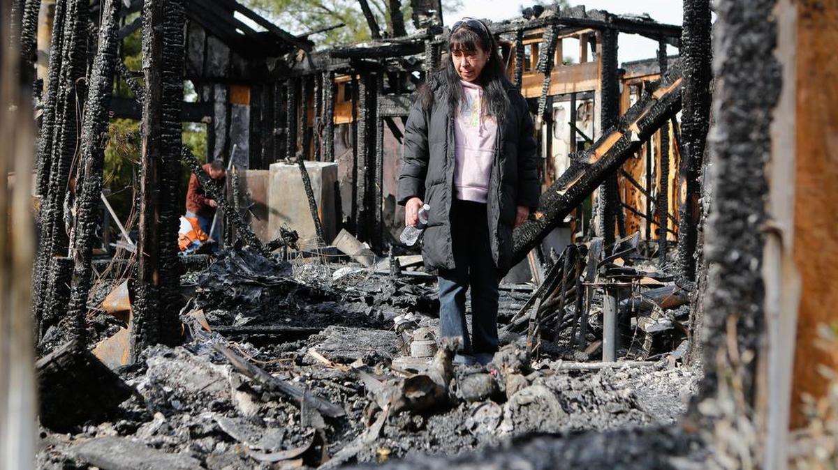 Jenifer Jowers walks through the ashes of her house .