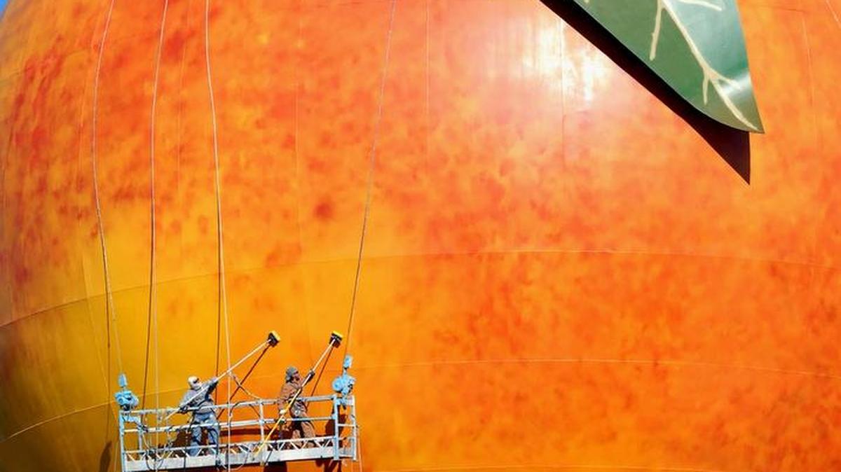 Workers use scrubbers to clean the outside of the Peachoid water tower in Gaffney, S.C.