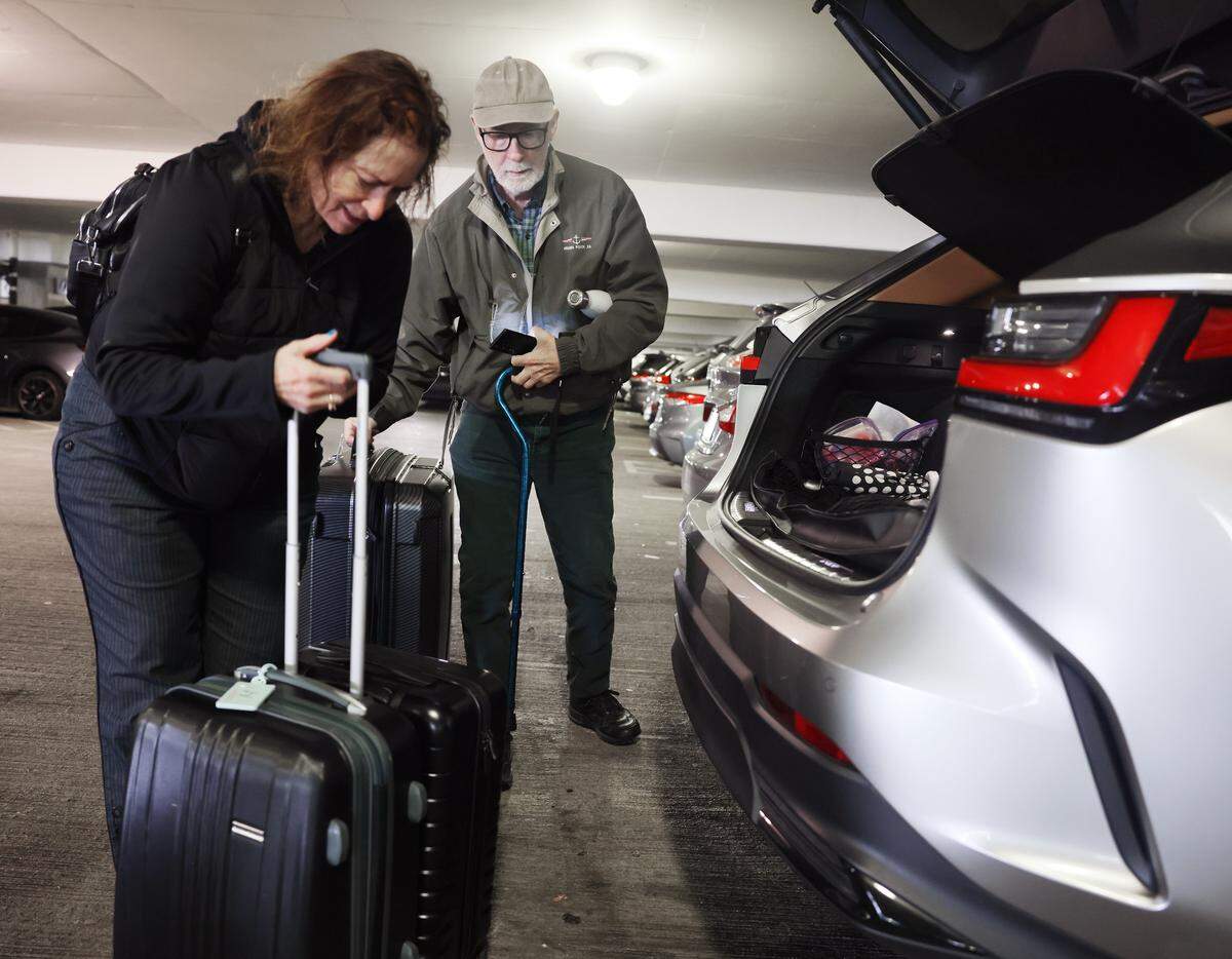 Betty and Martin Holmes remove luggage from their car at Charlotte Douglas International Airport on Tuesday, Jan. 27, 2026.