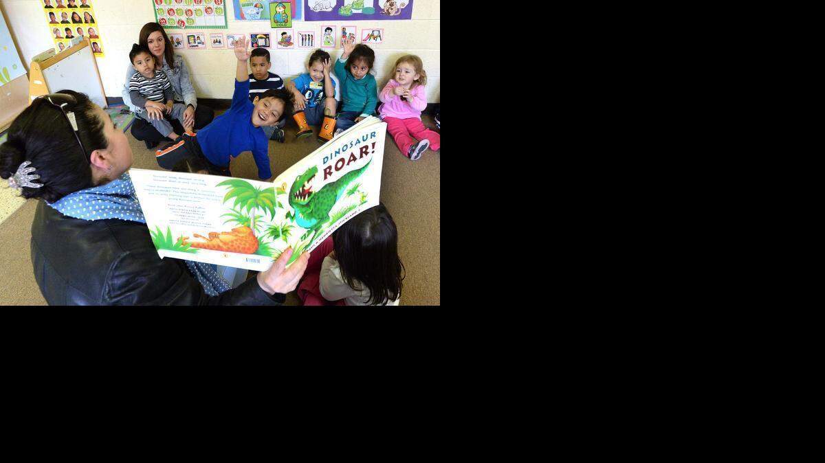 
 Charlotte Bilingual Preschool student Axel Albarran Mateo, 4, holds up his hand to answer a question while parent volunteer Ivonne Uquillas reads from the book “Dinosaur Roar.”  Sitting along the wall with teacher assistant Christina Klein are, from left, 3-year-olds Emmanuel Robles Venegas, Kenneth Sarante Viscaino, Alejandro Zeni Zuniga, Maya Hernandez Martinez and Emily Martinez.


