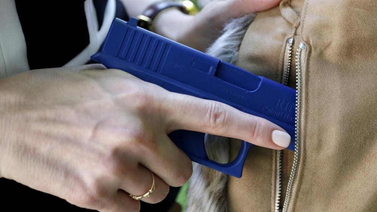 In this 2016 photo, Marilyn Smolenski uses a mock gun to demonstrate how to pull a handgun out of the concealed carry clothing she designs at her home in Park Ridge, Ill. Iredell County is considering allowing its government employees to carry concealed handguns in their offices and other work sites.
