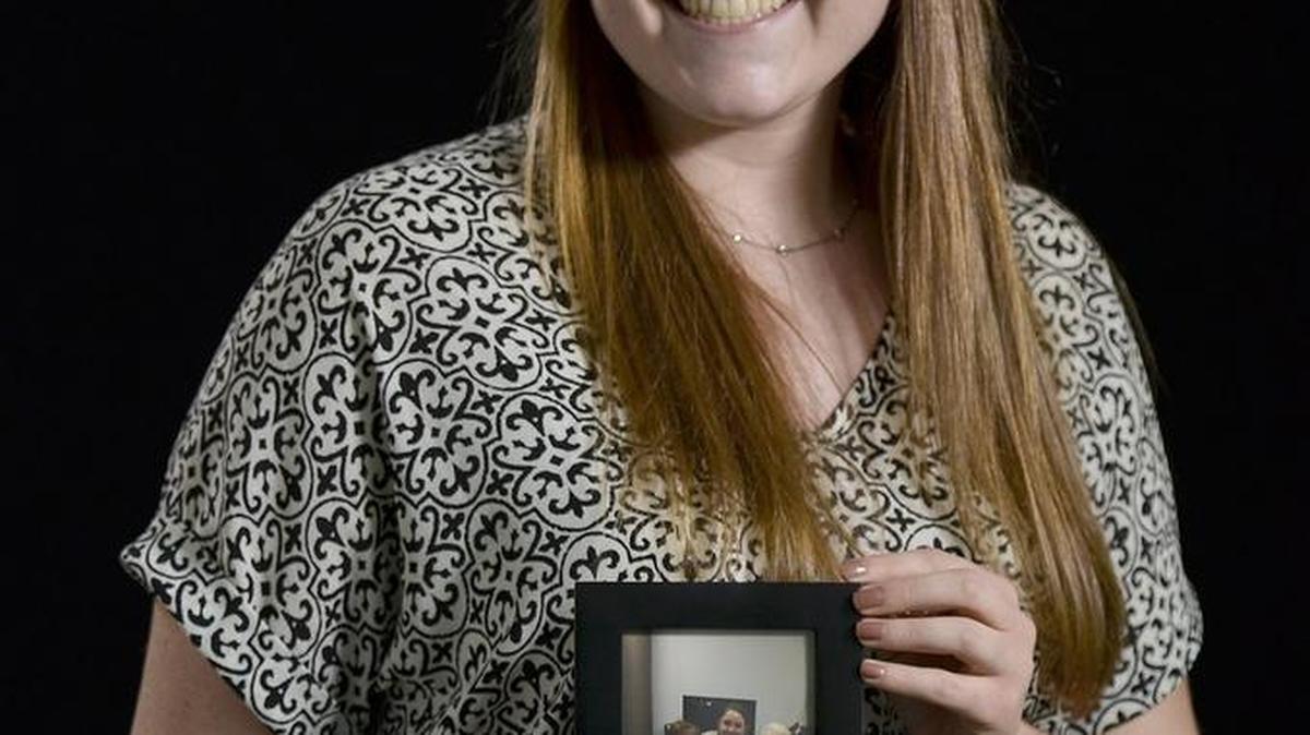 Alexandra Dawes holds a photo of two women who participated in her “Students Teaching Seniors” program.