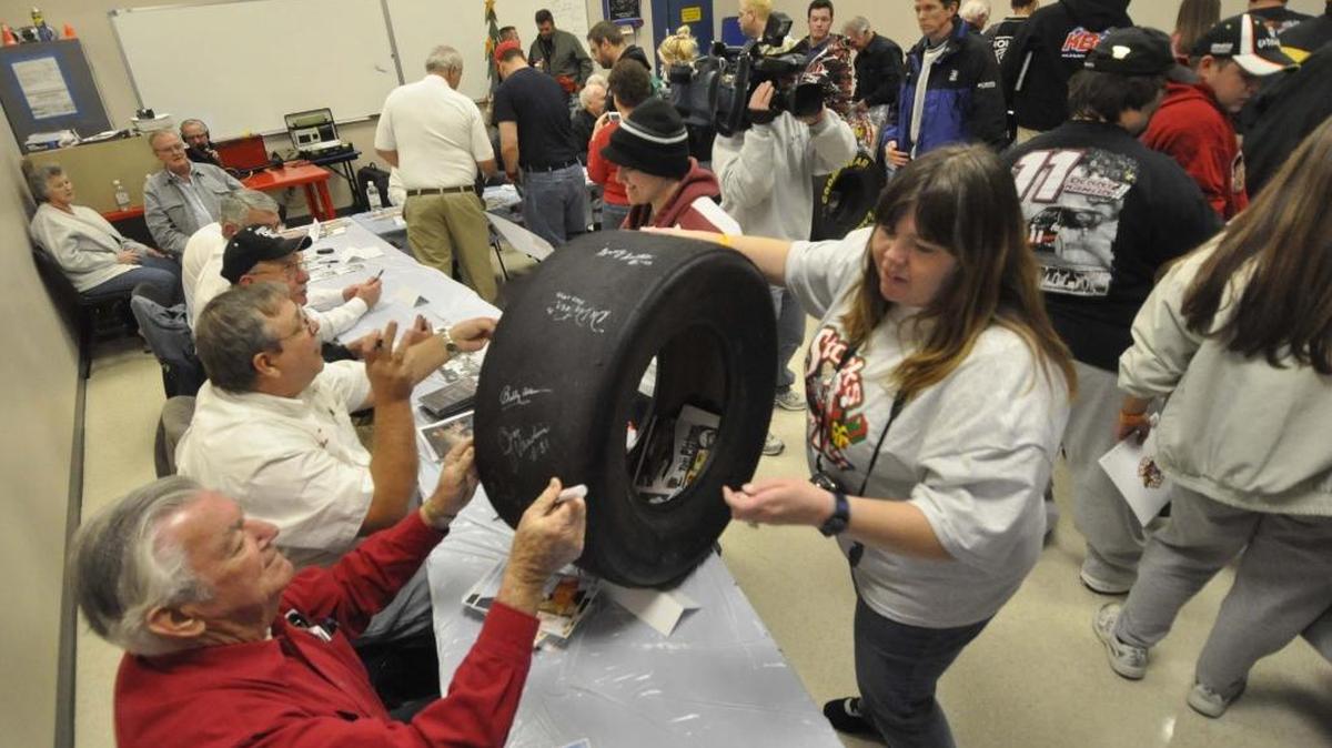 NASCAR legend and retired driver Bobby Allison signs a tire for NASCAR fan Tammy Tavares of Atlanta at the 2015 Stocks for Tots benefit in Mooresville. The 2021 event is 6:30- 8:30 p.m. Dec. 7 at the Charles Mack Citizen Center in downtown Mooresville.