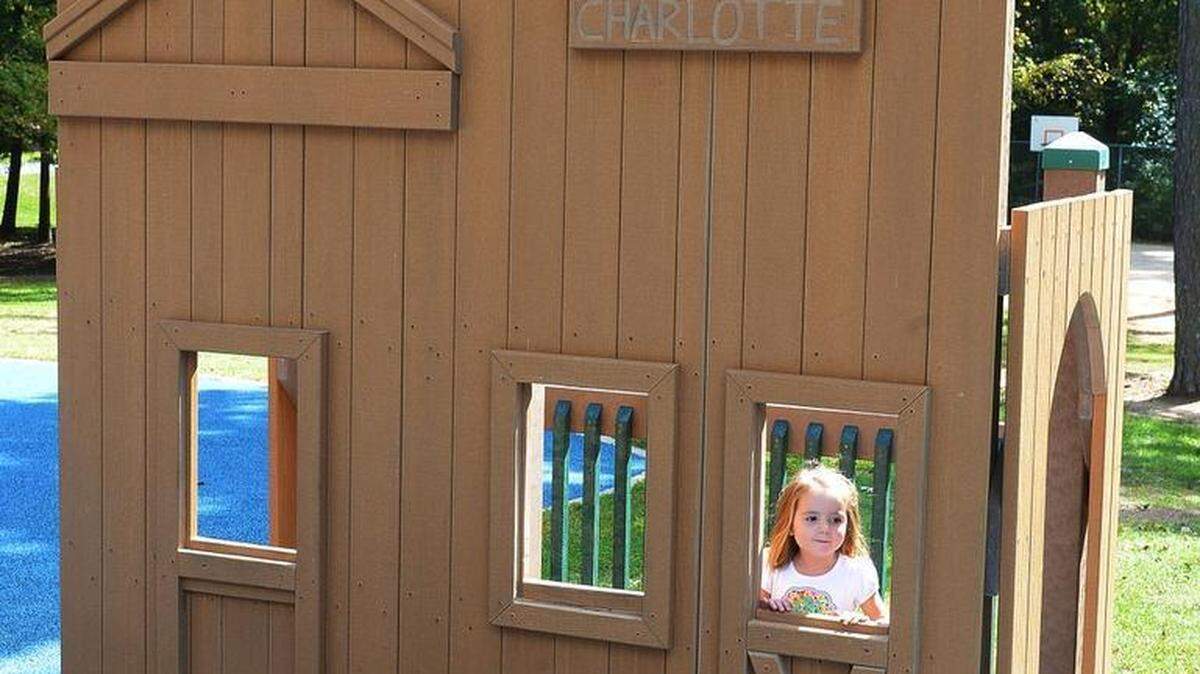 
A girl plays on the children's playground at Park Road Park around a replica of a general store with a red cross emblazoned on the front on Monday. The county removed the cross when a Charlotte mother said she found it ostracizing and offensive.

