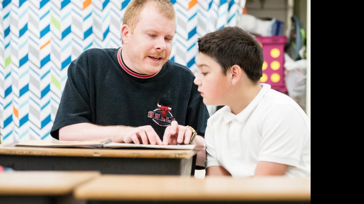 
Joseph Pi–a watches Jeff Balek read brail and help him with words he is having trouble with at Nations Ford Elementary School in Charlotte on May 11, 2015. Jeff reads along with students who are at risk to fall behind in reading comprehension and reads along with the students to help them learn difficult words in the book. 
