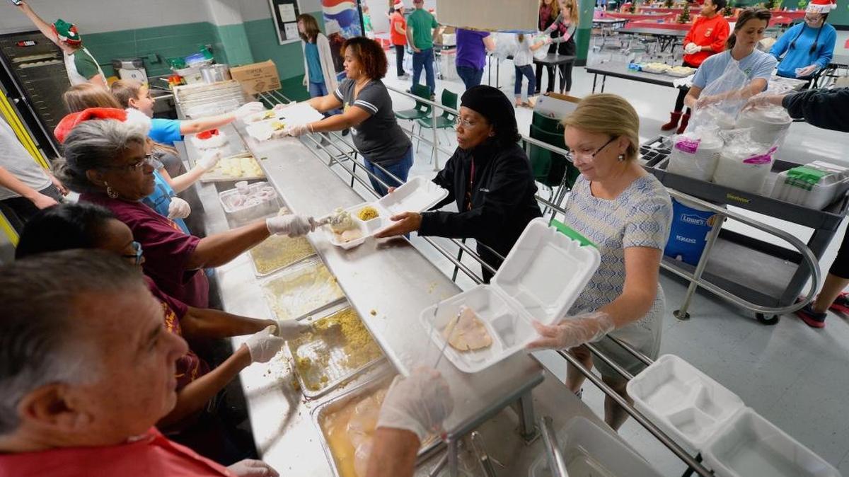 Volunteers Zundrea Baldwin, top right, Regina Kay, center right, and Lisa Ferguson-Graham, bottom right, wait as volunteer servers fill cartons with meals for those in need on Christmas Day at St. Patrick’s Cathedral in Dilworth. Volunteers prepared the meals and delivered them to anyone in the community.
