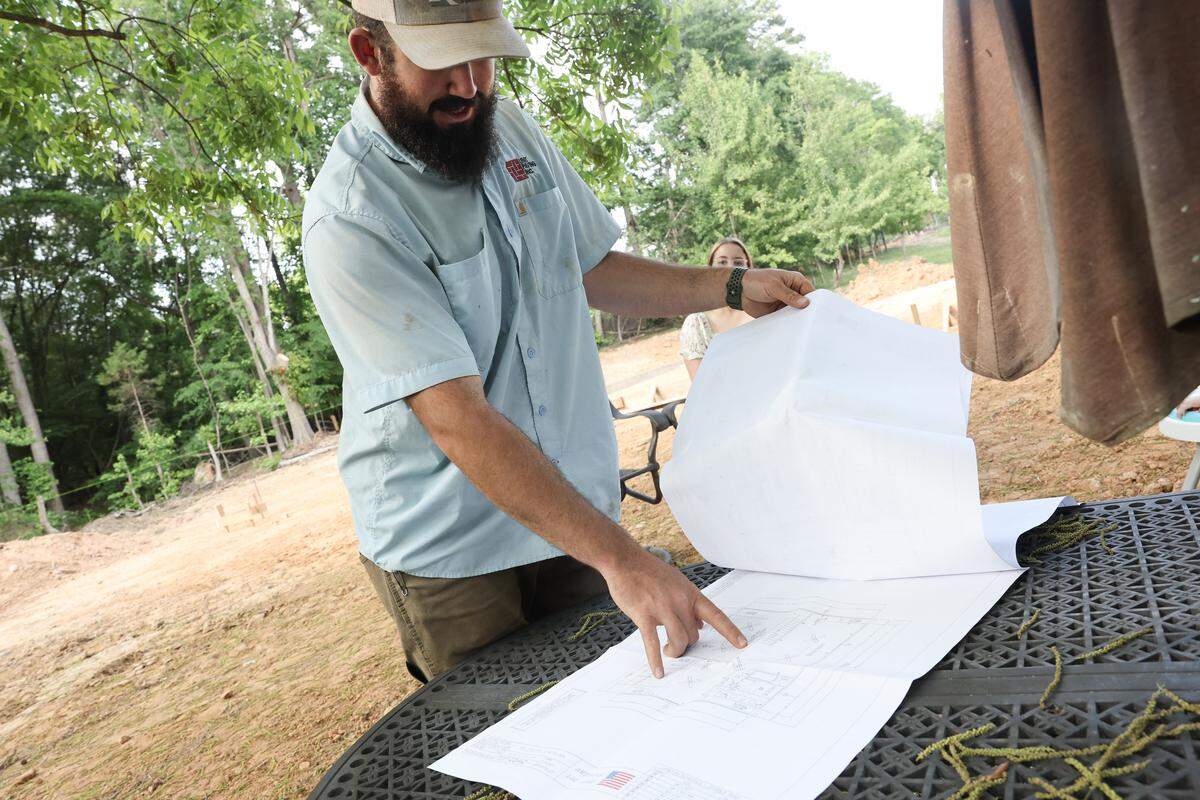 Cody Benfield looks over plans he had made after he bought a log cabin package.