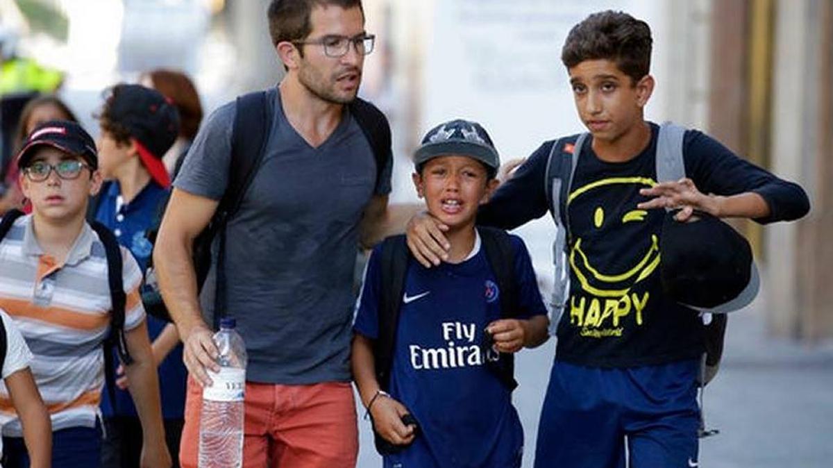 Children, some in tears, are escorted down a road in Barcelona, Spain, Thursday, Aug. 17, 2017. Police in Barcelona say a white van has mounted a sidewalk, struck several people in the city's Las Ramblas district.