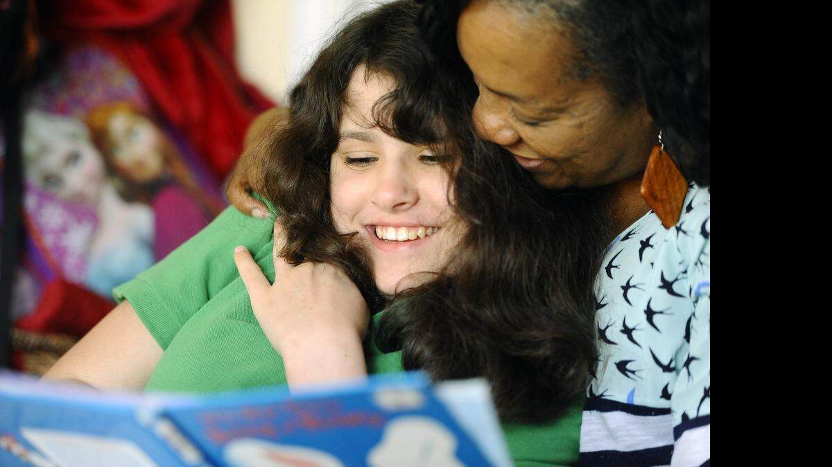 
Bewlay Koury,12, smiles as she reads a book with her caregiver Carol Summers while at home on Tuesday, March 17, 2015. This has been the first year that Cardinal Innovation has handled behavioral health services for all Medicaid clients in Mecklenburg County. Christy Koury has struggled to get what she thinks her 12-year-old daughter, Bewlay, needs to deal with her severe developmental disorder. 
