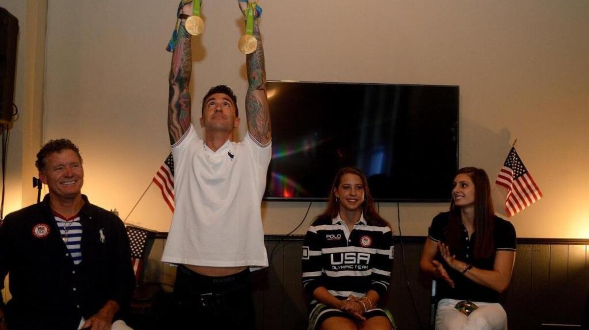 Olympic gold medal winner Anthony Ervin holds up his two gold medals as he speaks along with Olympic swimmers Kathleen Baker and Katie Meili during an Olympic swimmer greeting on Sunday at Port City Club in Cornelius. At left is Olympic swim club coach David Marsh.