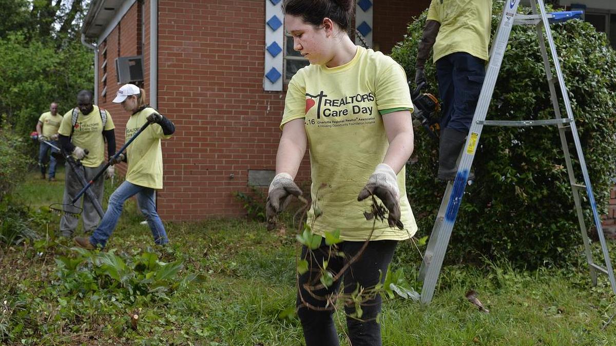 Realtor Erika McNew along with fellow Realtors clean overgrown weeded yards in in the Druid Hill community.