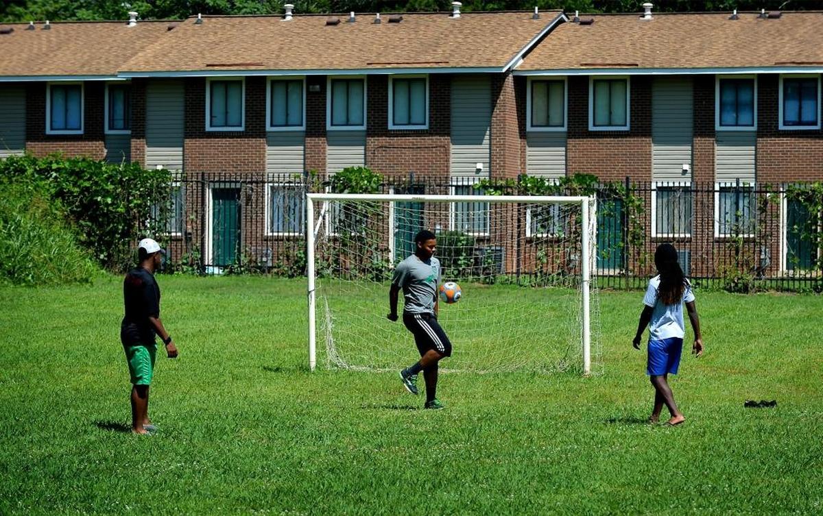 Tyree Watson, left, Jah'Qwel Williams, center and Deron Huggins, right, kick a ball around at the field in Grier Heights.