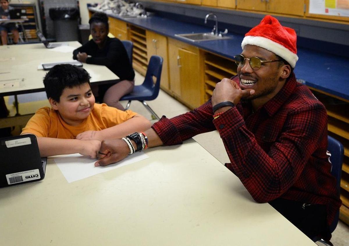 Carolina Panthers quarterback Cam Newton, right, sits with students in art class at Sedgefield Middle School on Tuesday during his Santa Cam’s Surprise Sleigh annual event.