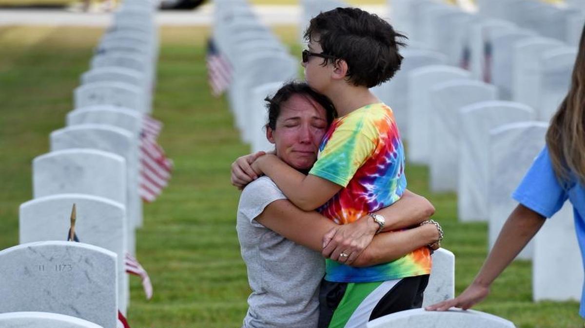 Paula Ackerman and her son Bryan, 8, hug at the grave marker of her father, Robert P. Vallee, who served in the Navy for more than 31 years at the Jacksonville National Cemetery, in Jacksonville Fla., on Saturday.