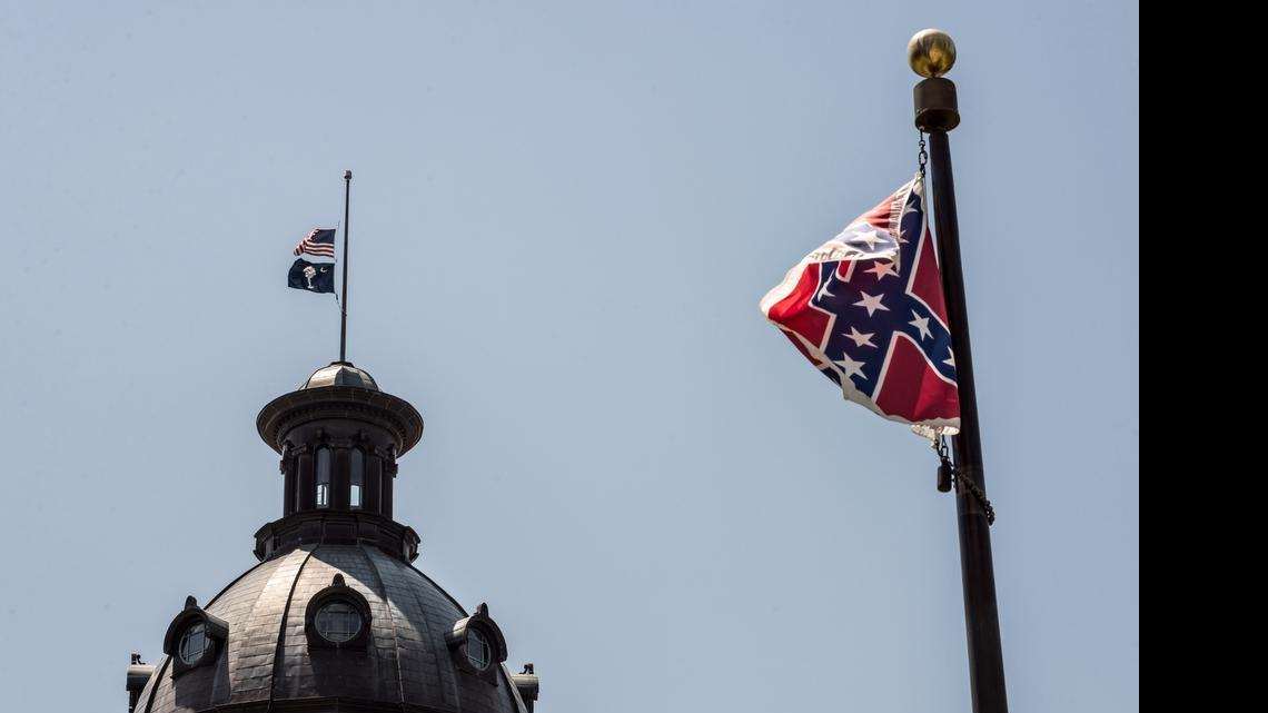 
COLUMBIA, SC - JUNE 18: The South Carolina and American flags fly at half mast as the Confederate flag unfurls below at the Confederate Monument June 18, 2015 in Columbia, South Carolina. Legislators gathered Thursday morning to honor their co-worker Clementa Pinckney and the eight others killed yesterday at Emanuel AME Church in Charleston, South Carolina. (Photo by Sean Rayford/Getty Images) 
