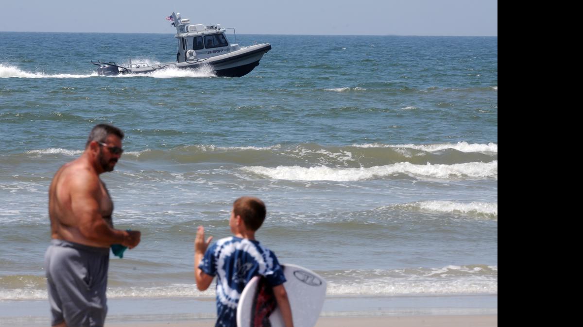 
Jack Cross, 9, watches as a boat patrols the coastline near Ocean Crest Pier in Oak Island on Monday, a day after two young people lost limbs in separate shark attacks. 
