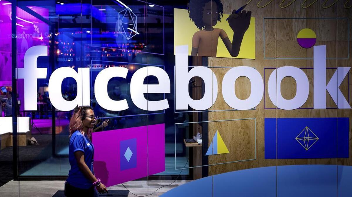 A conference worker passes a demo booth at Facebook’s annual F8 developer conference in San Jose, Calif., last month.