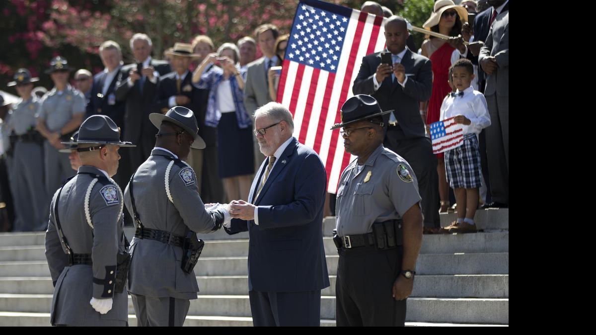 
A trooper hands the Confederate flag to Allen Roberson, director of the Confederate Relic Room and Military Museum.
