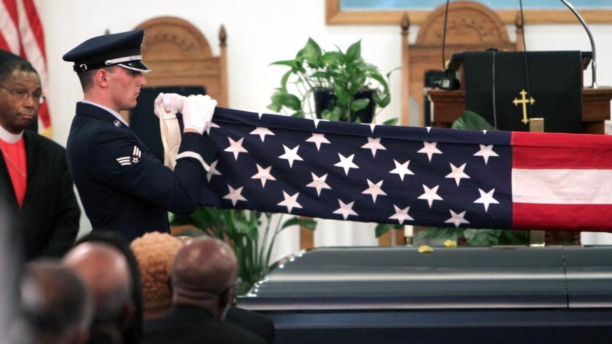 A member of the U.S. Airforce Honor Guard unfolds an American flag to place over the casket of Clarence Graham Friday at Boyd Hill Baptist Church.