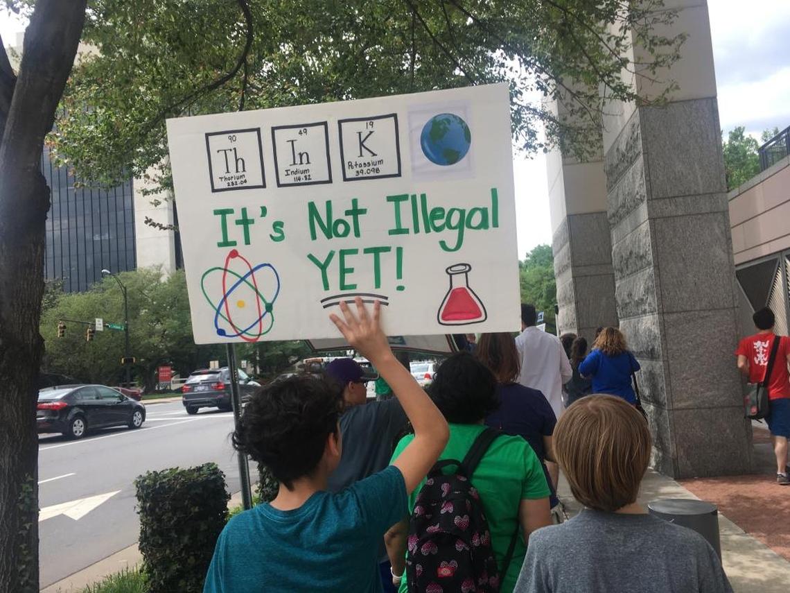 People held signs condemning budget cuts to science research and demanding action on climate change.