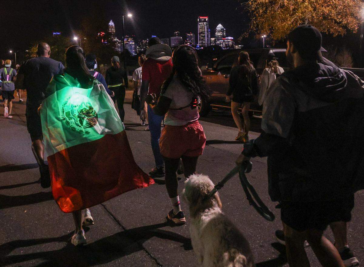 Miri Cortez dons a large Mexican flag, tied around her neck like a cape, as she joins Charlotte’s Latino run club for its weekly run on Wednesday, Nov. 19. Earlier in the week U.S. Border Patrol and Immigration and Customs Enforcement began operations in Charlotte. Despite fear in the community, the run club decided to go out and represent their culture. 